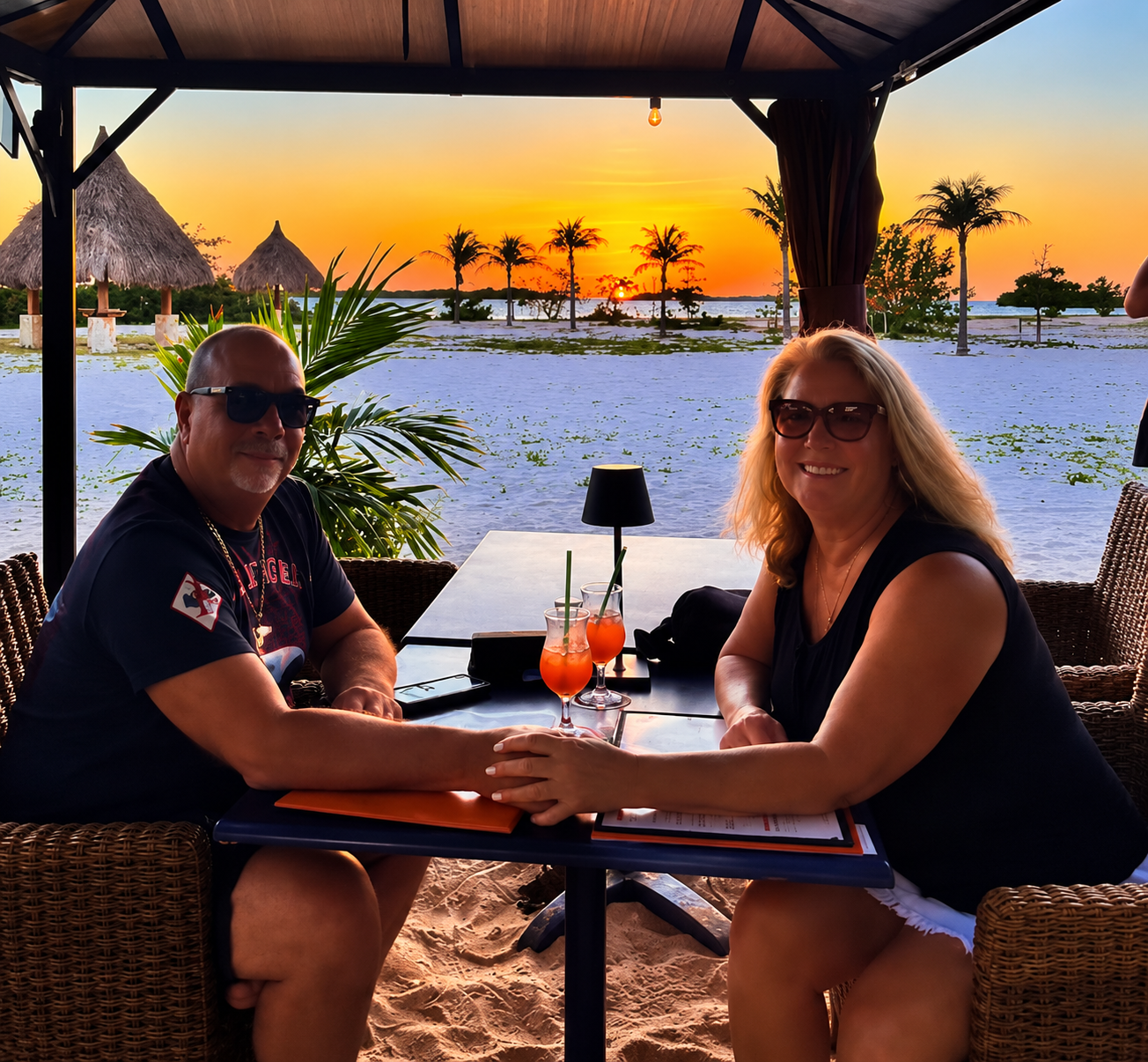 Couple enjoying a sunset dinner at a beachfront table at Battata