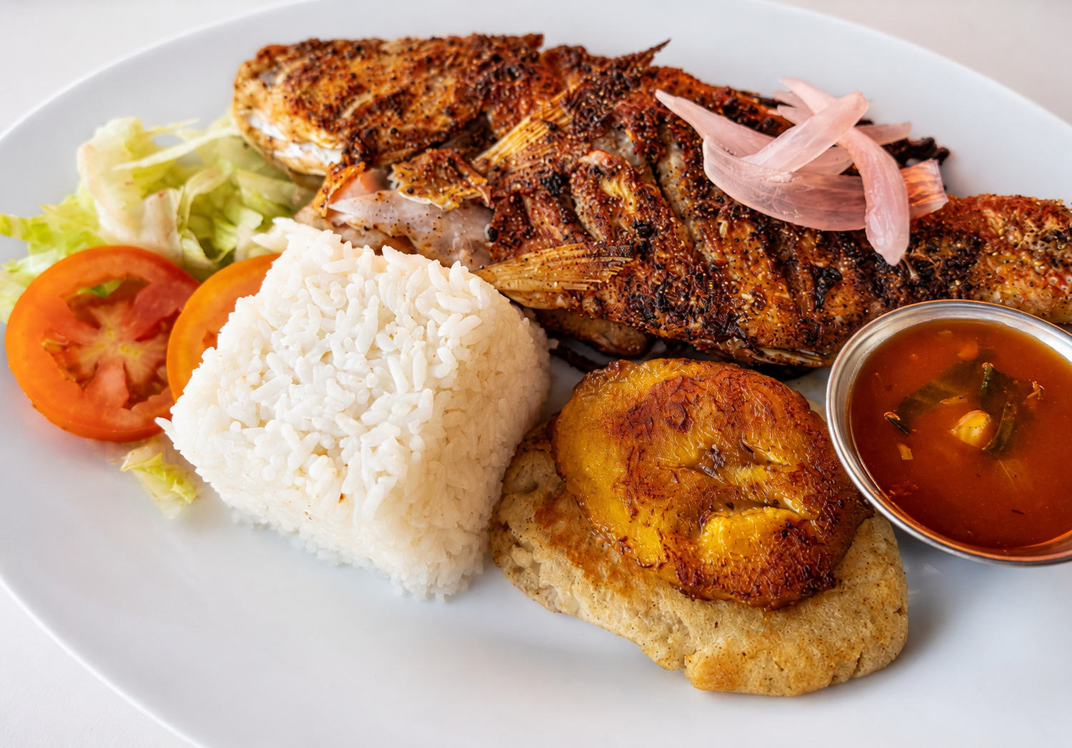 Grilled whole fresh fish with rice, plantain and salad