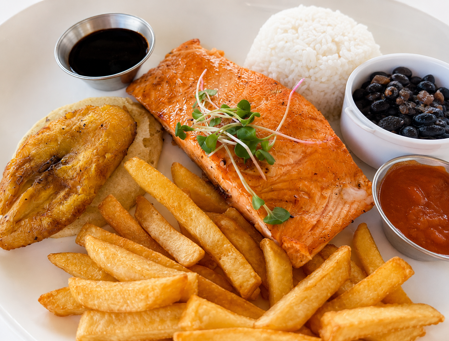 Grilled salmon plate with fries, rice and black beans